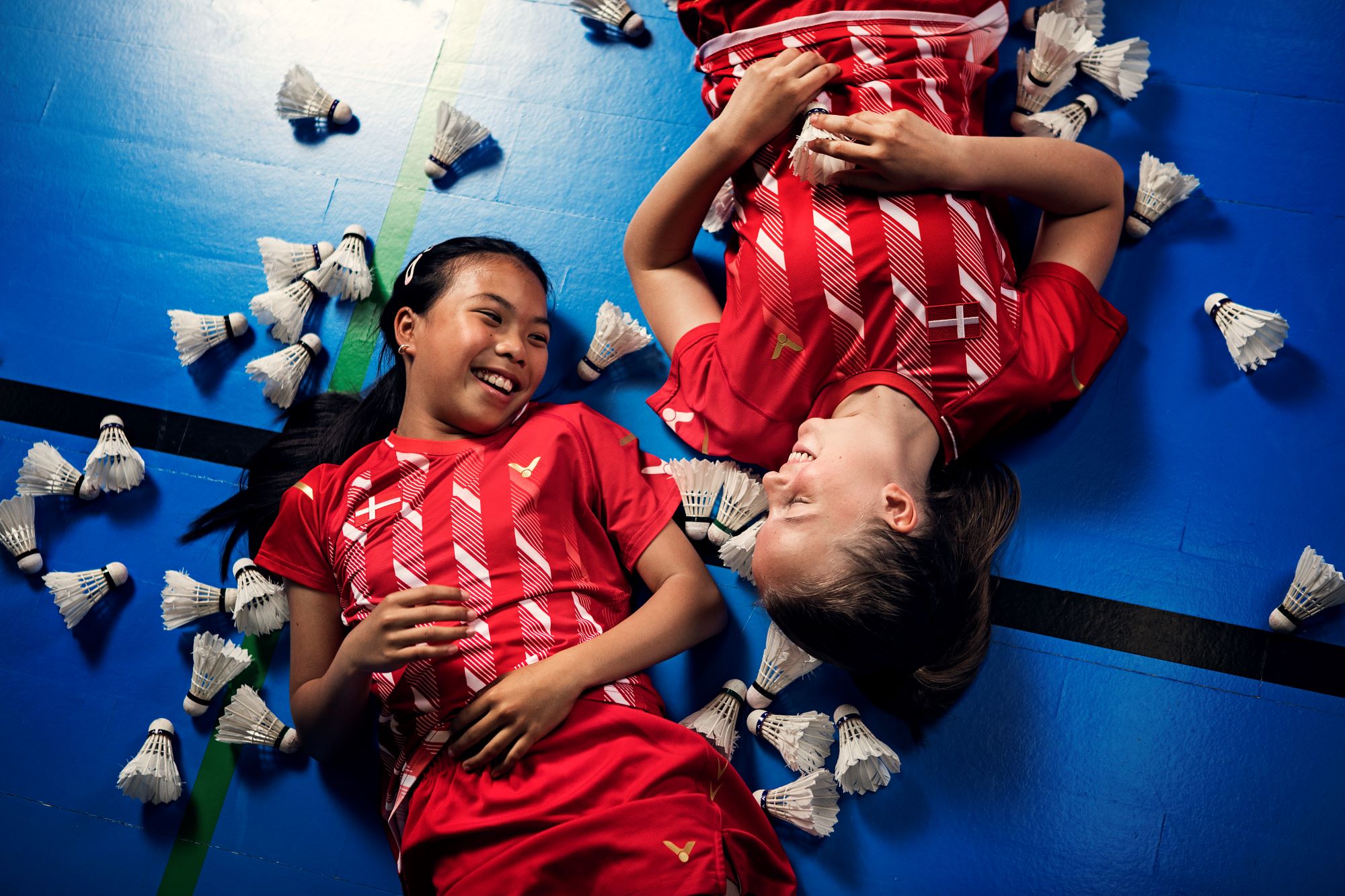 Lille To Glade Piger Ligger På Gulvet I Badminton Hal