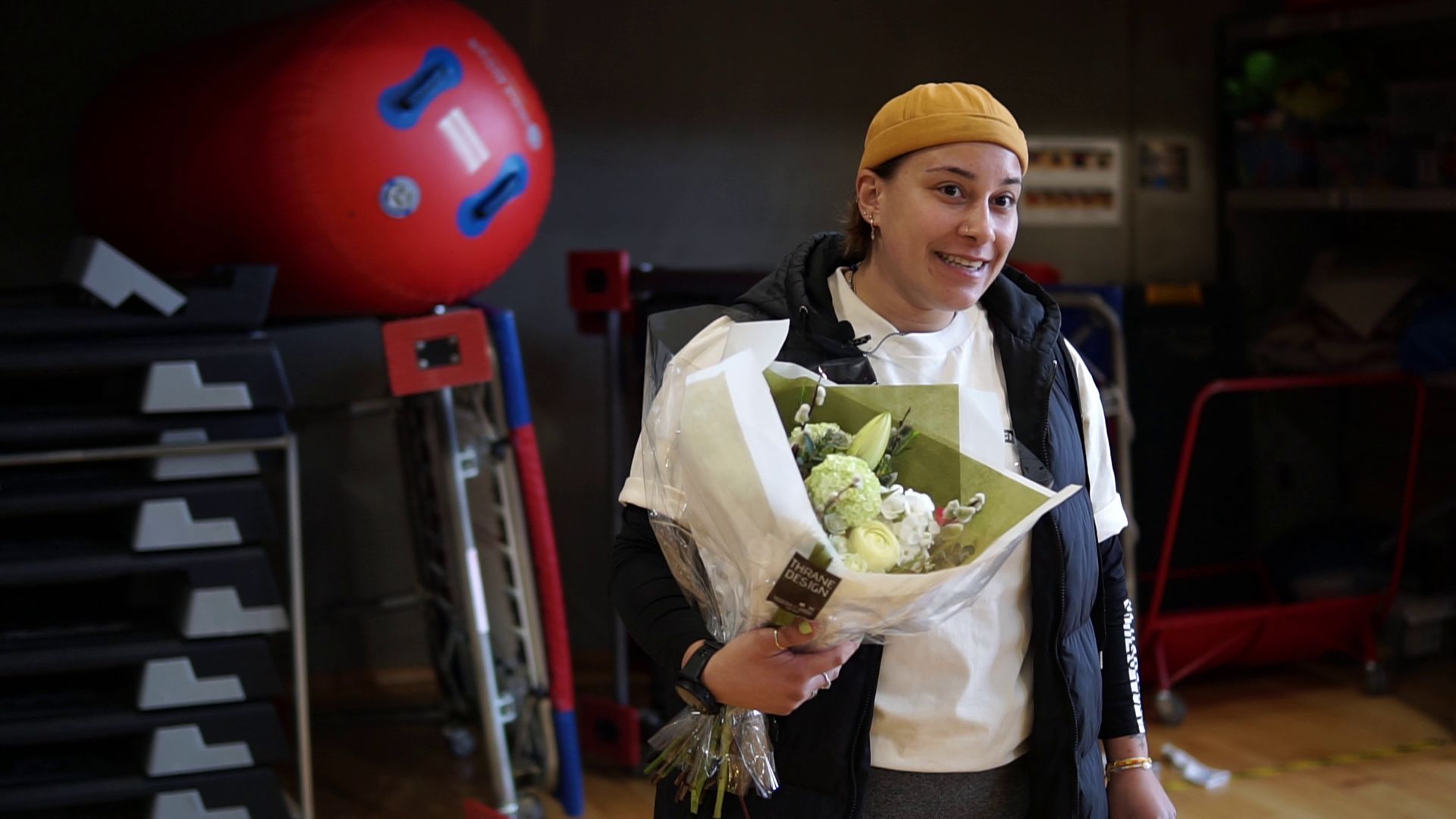 Allai Abou-Chaker fra DGI Østjyllands bestyrelse afbryder træningen og overrækker blomster og prisen til en overrasket Mathilde midt i hallen i Lyseng Idrætscenter